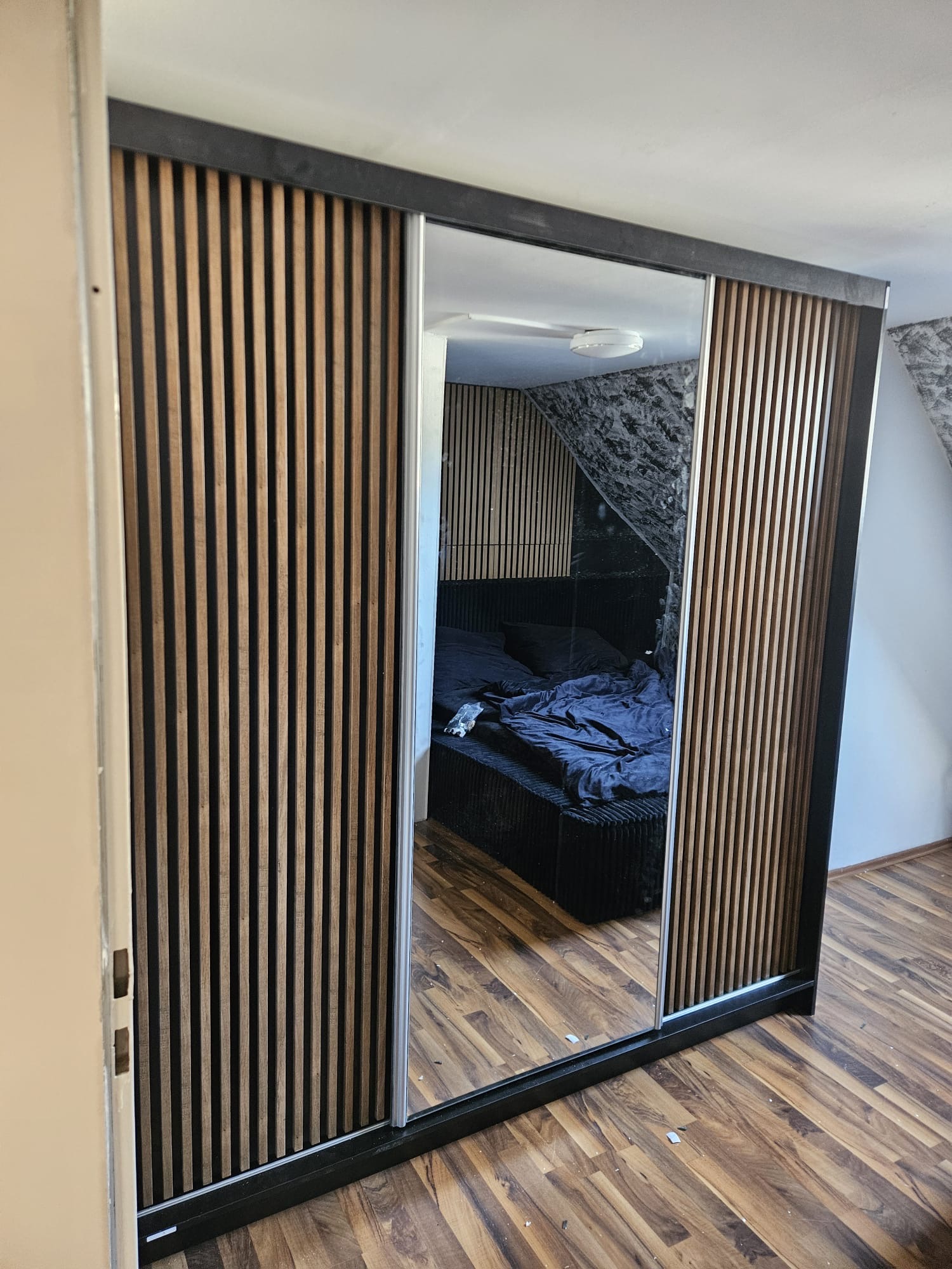 Montierter Schwebetürenschrank mit Spiegel und Holzlamellen